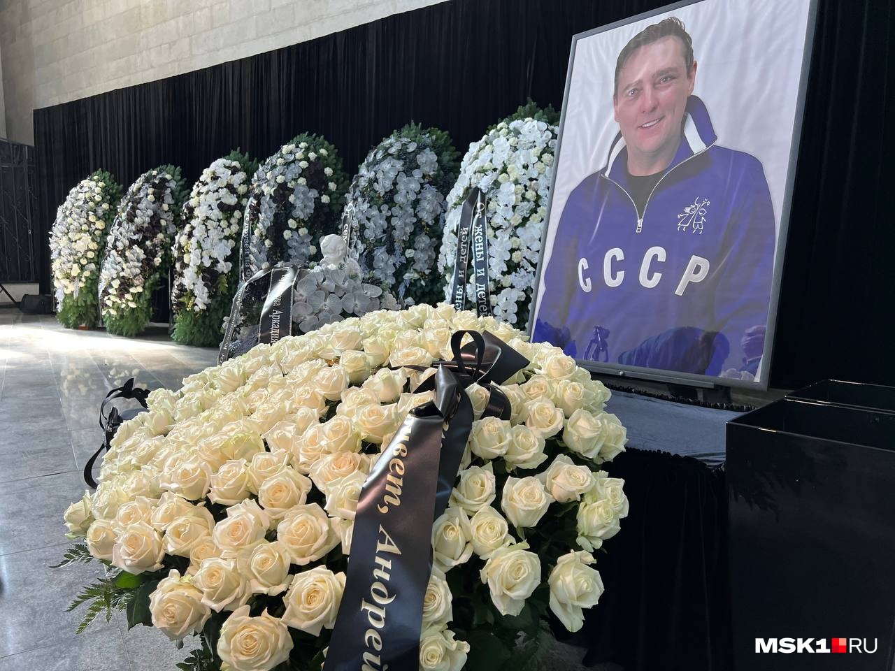 В траурном зале стояли огромные портреты Юрия Шатунова в окружении букетов из белых роз В траурном зале стояли огромные портреты Юрия Шатунова в окружении букетов из белых роз