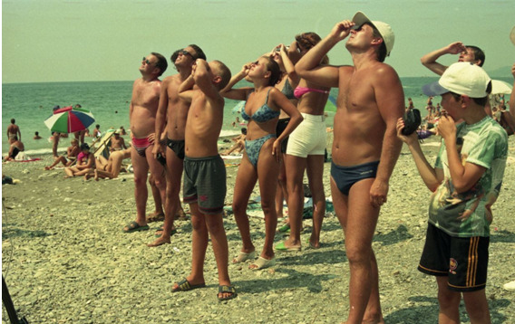 Отдыхающие на пляже в Сочи смотрят на солнечное затмение через темные стекла 11 августа 1999 года