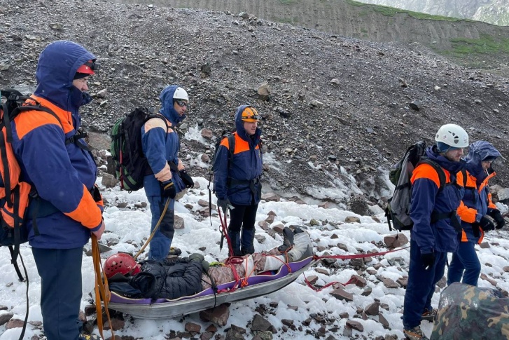 Группа спасателей спустила пострадавшего на носилках на равнину