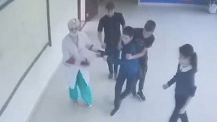 На фото видно, что медработник и несколько школьников пытаются схватить ребенка