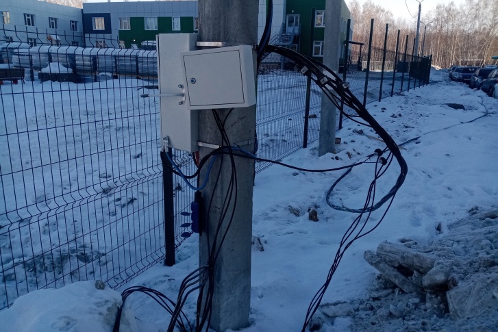 Электрошкаф с проводами находится недалеко от нового детского сада в Парковом