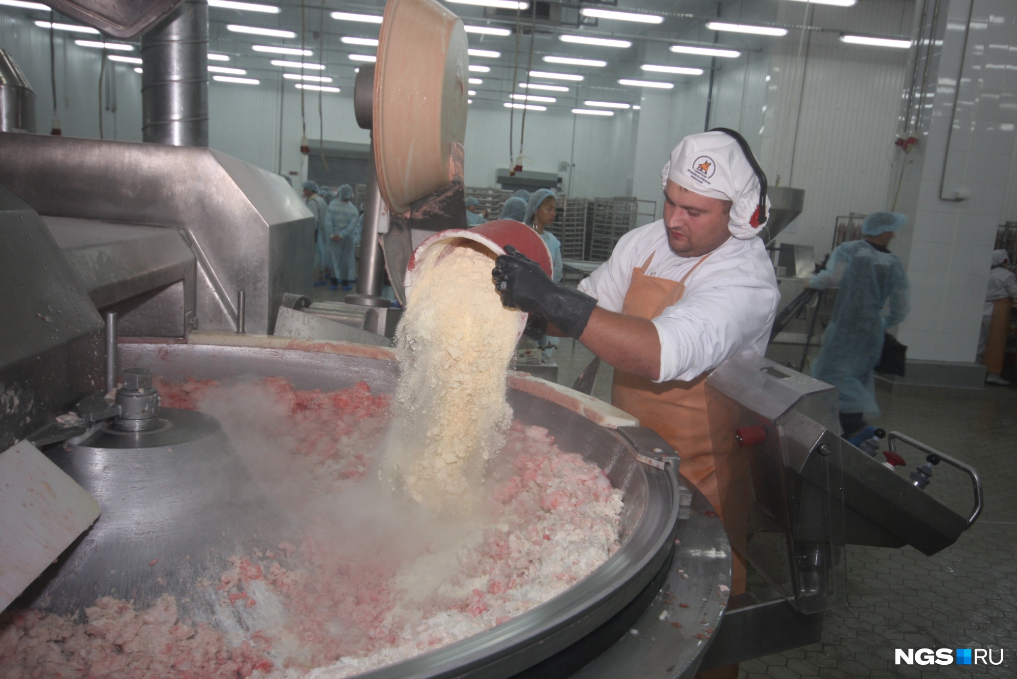Подготовка фарша для вареной колбасы. На фото работник добавляет в фарш смесь из яичного порошка и сухого молока