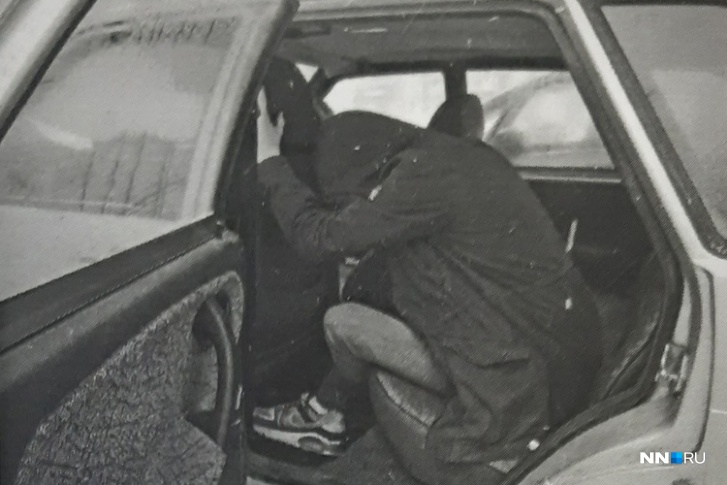 Роман Мишин показывает правоохранителям, как ему указали сидеть в машине преступники: вытянуть руки, опустить голову и надеть капюшон