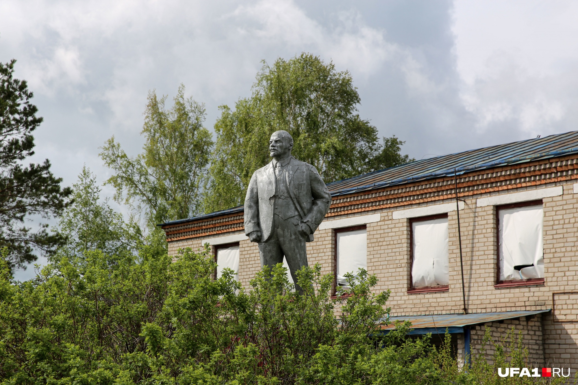 Памятник Ленину выглядывает из зарослей