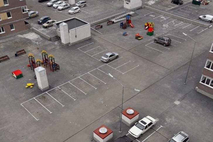 Разметка для парковки автомобилей находится в паре метров от детских площадок