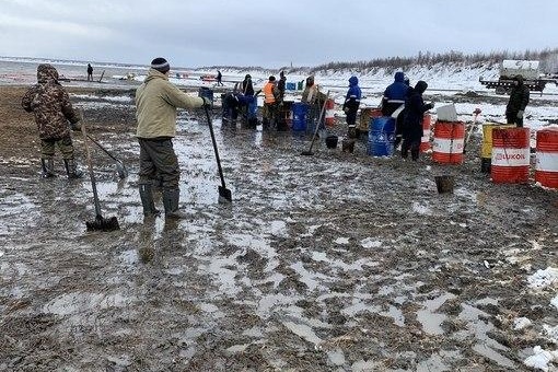 Люди собирают смесь грунта и нефти Люди собирают смесь грунта и нефти