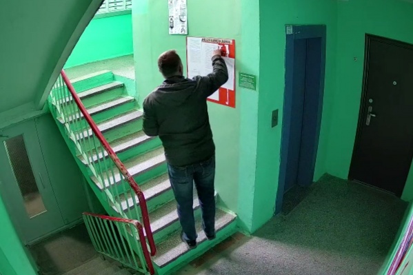 Человек методично срывает объявления с предложением провести собрание Человек методично срывает объявления с предложением провести собрание