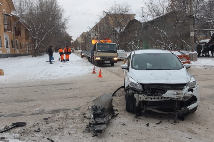 Разбитый Ford и дорожные рабочие (на заднем плане), восстанавливающие знак приоритета Разбитый Ford и дорожные рабочие (на заднем плане), восстанавливающие знак приоритета