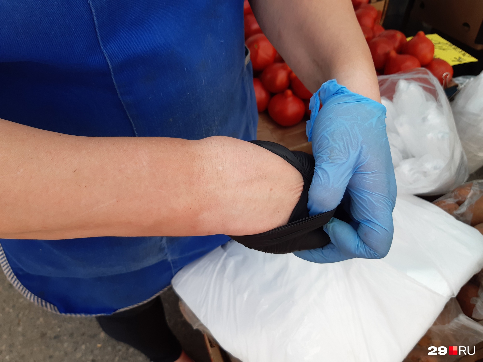 Продавец овощей, ягод и фруктов Анна показывает профессиональный загар по перчатку