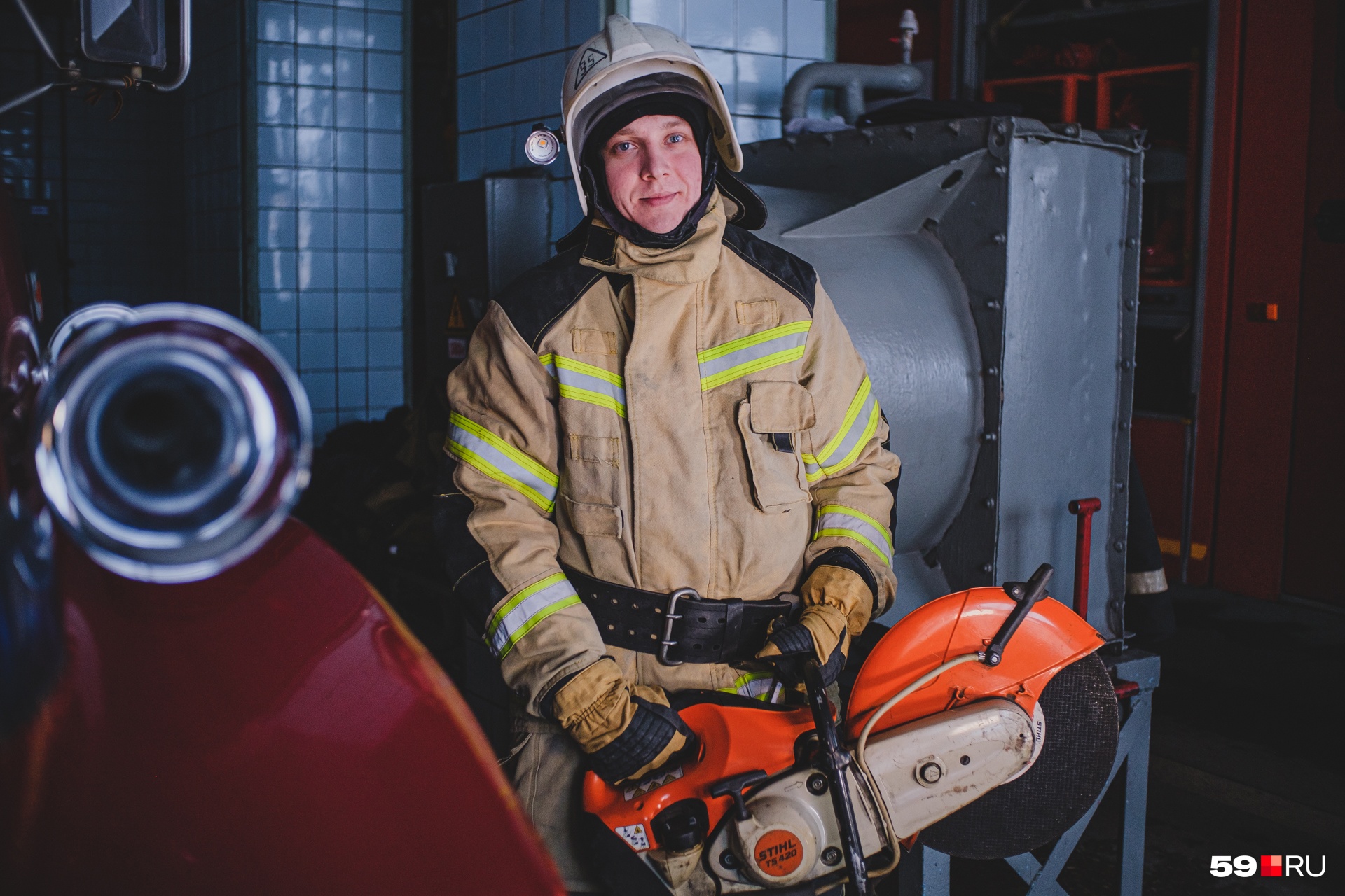 Максим Логинов держит в руках бензорез, который помогает пожарным разрезать стальные двери или тросы
