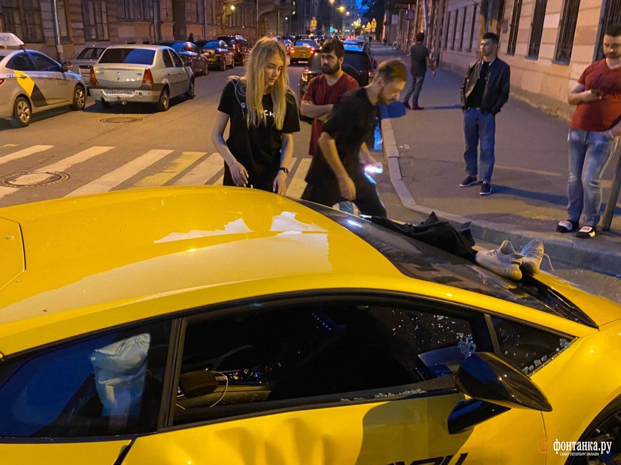 Жёлтый Lamborghini затормозил о тротуар в центре Петербурга. В ожидании служб на капоте отдыхает девушка без ботинок