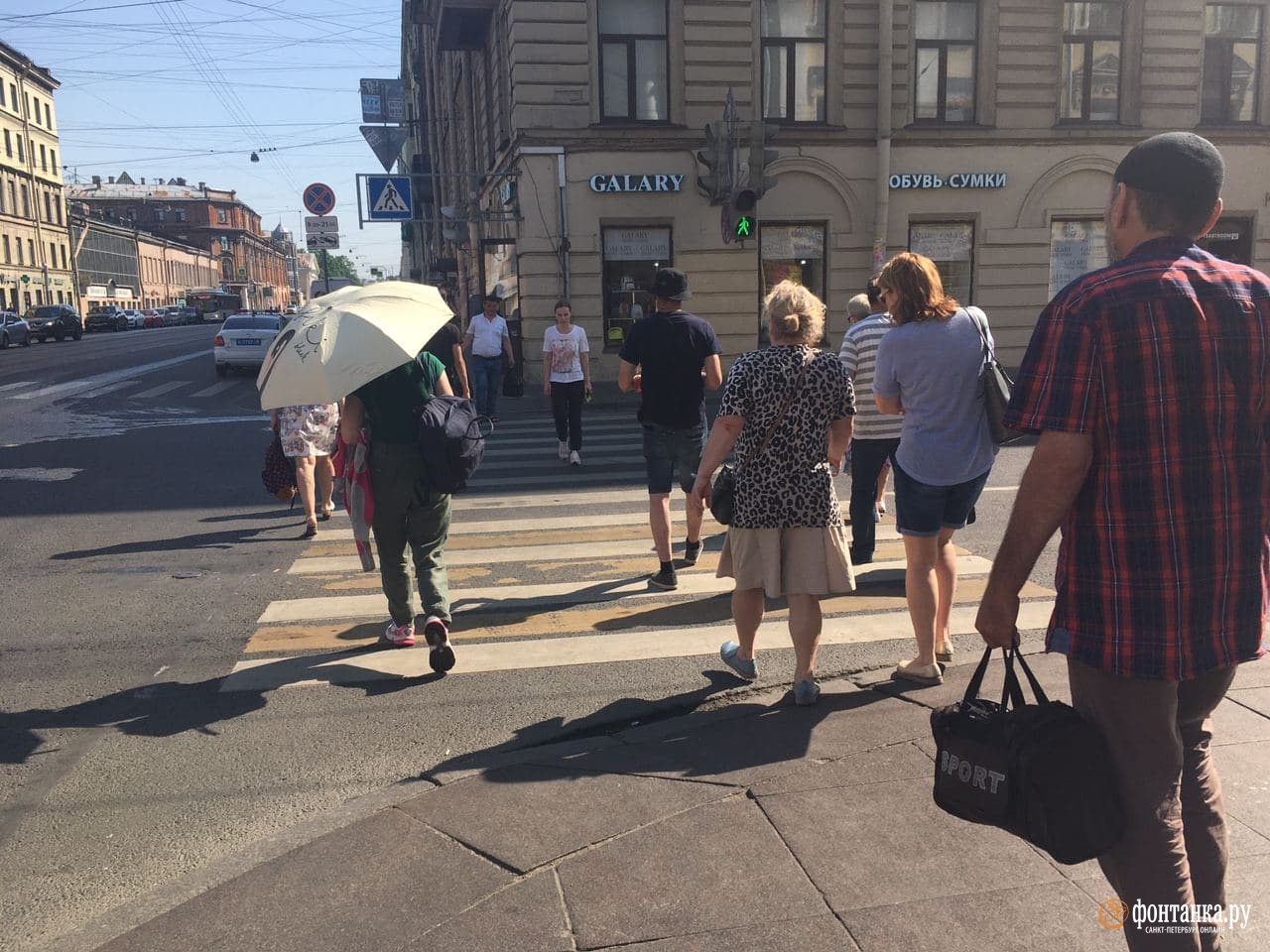 Петербуржцы прячутся от палящего солнца под зонтиками.