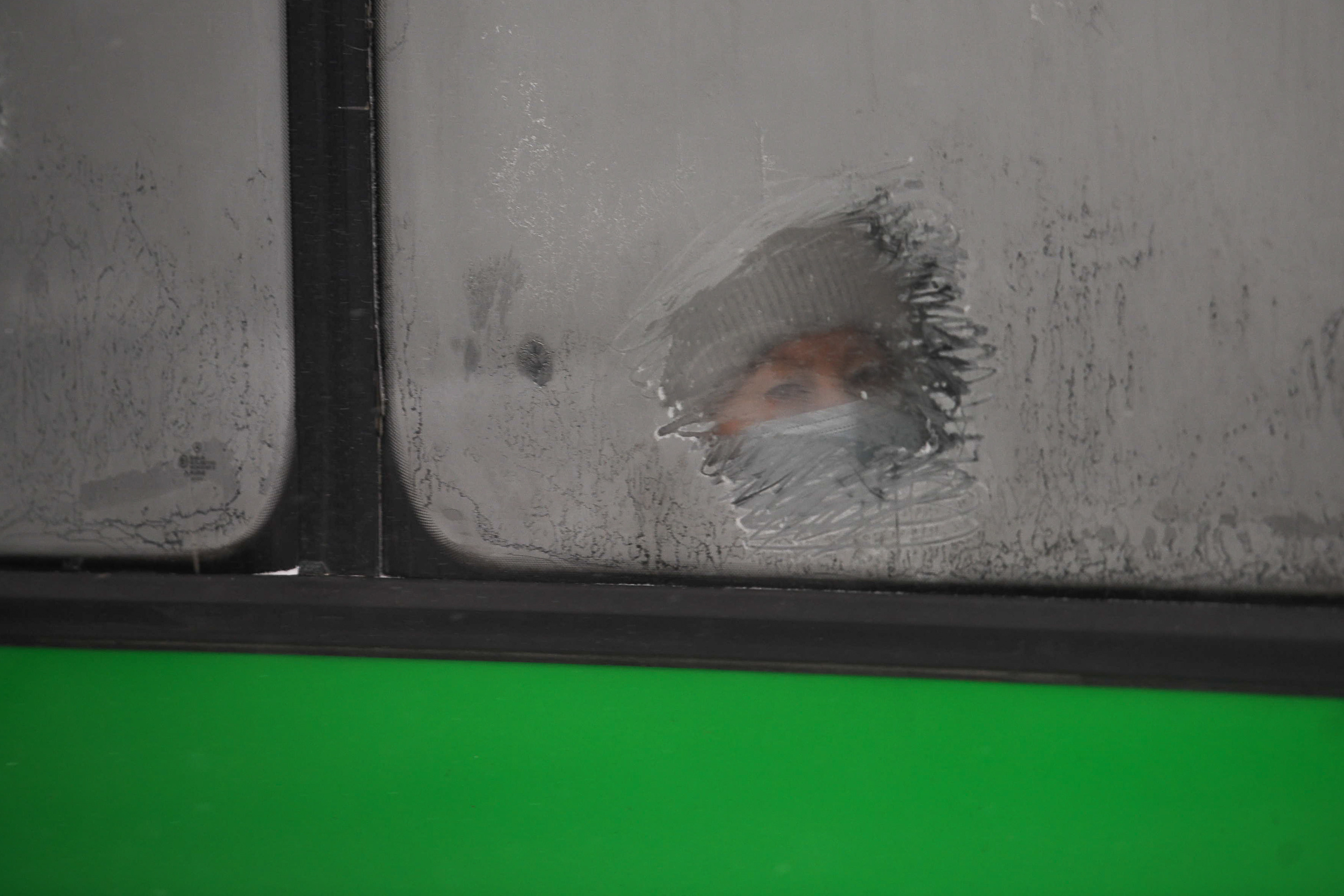 Пассажиры общественного транспорта вынуждены наблюдать мир через маленькие прорехи в замерзших окнах
