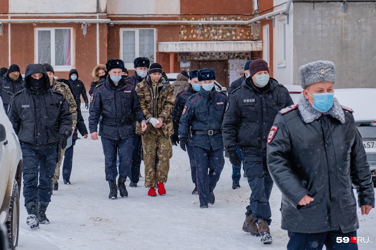 Подозреваемого ведут в плотном окружении полицейских Подозреваемого ведут в плотном окружении полицейских
