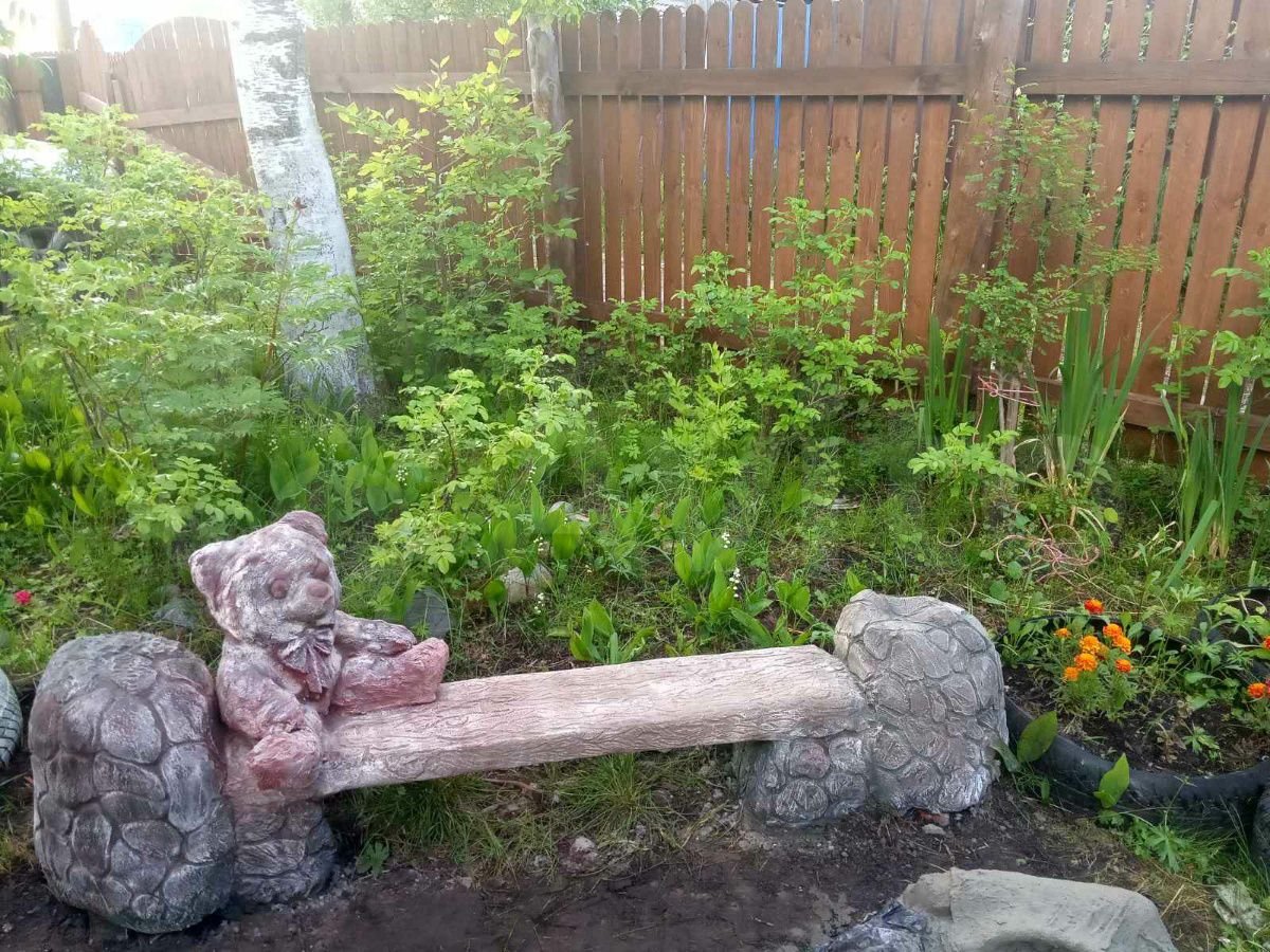 Плюшевый медведь сидит на веранде, его собрат отдыхает в саду