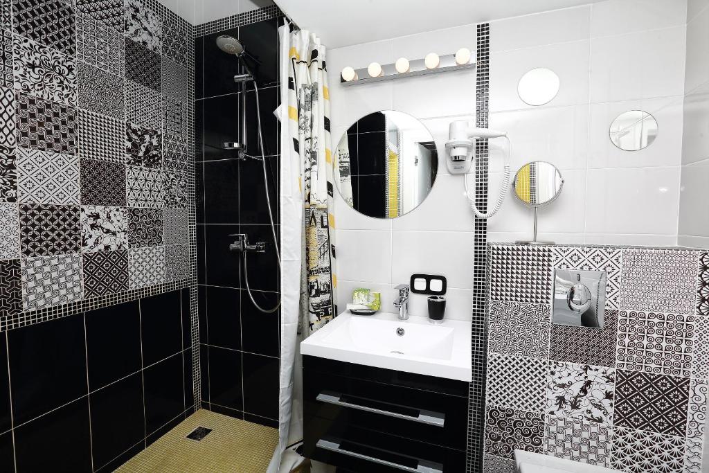 Ванная комната оформлена в черно-белых тонах с лимонными вкраплениями. Есть настенное и потолочное освещение помещения