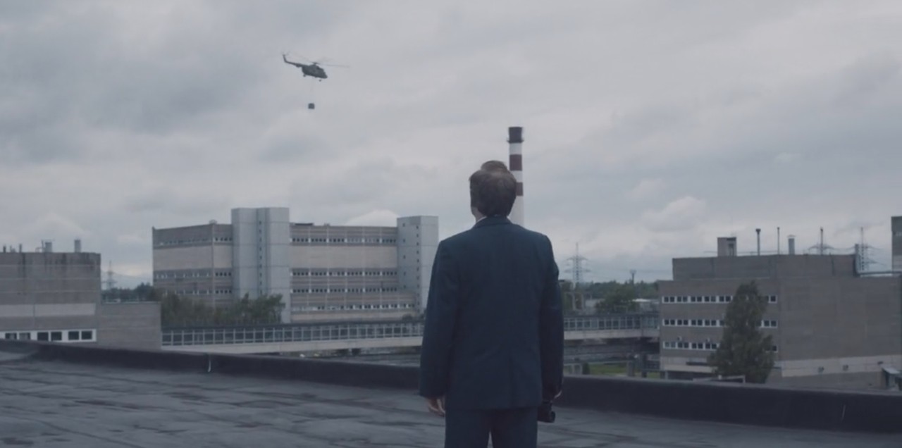 Кадр из сериала «Чернобыль»: Валерий Легасов наблюдает, как вертолет тащит к реактору мешки с песком, упакованные в парашют