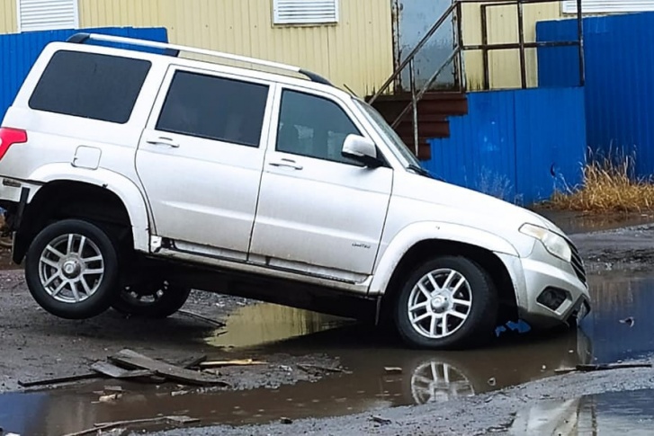 Автомобиль провалился одним колесом в яму и застрял. Очевидно, водитель не ожидал, что лужа окажется настолько глубокой Автомобиль провалился одним колесом в яму и застрял. Очевидно, водитель не ожидал, что лужа окажется настолько глубокой
