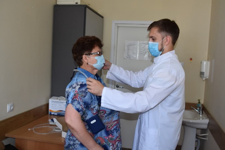 Врач одевает на пациентку аппарат для суточного мониторирования Врач одевает на пациентку аппарат для суточного мониторирования