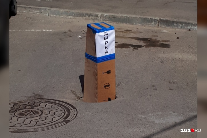 Коробка с надписью «Дырка» торчит из ямы в центре города