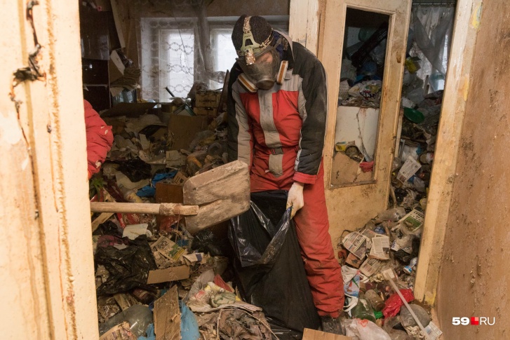 Оставшийся мусор из квартиры бабушки убирают в респираторах
