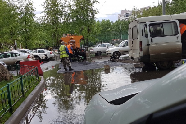 Мужчины укладывают асфальт около огромной лужи на улице Садовой Мужчины укладывают асфальт около огромной лужи на улице Садовой 