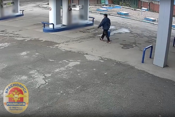 Мужчина набирает бензин в синее пластиковое ведро Мужчина набирает бензин в синее пластиковое ведро