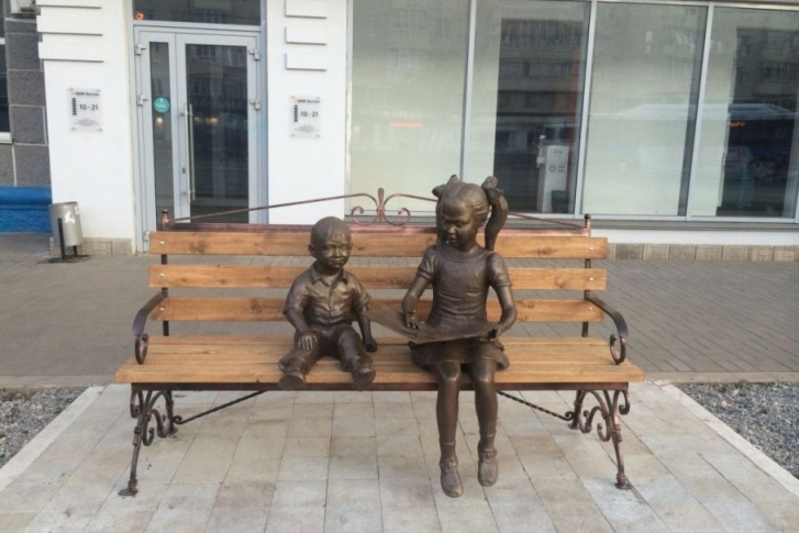На скамейке «поселились» мальчик и девочка с книгой