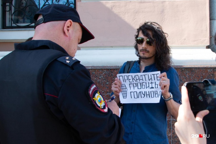 Полицейский переписывает паспортные данные Артема Келарева, который встал в одиночным пикетом 