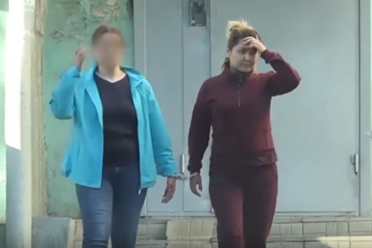 Момент, как сотрудник полиции выводит Хайруллину из подъезда дома в Казани