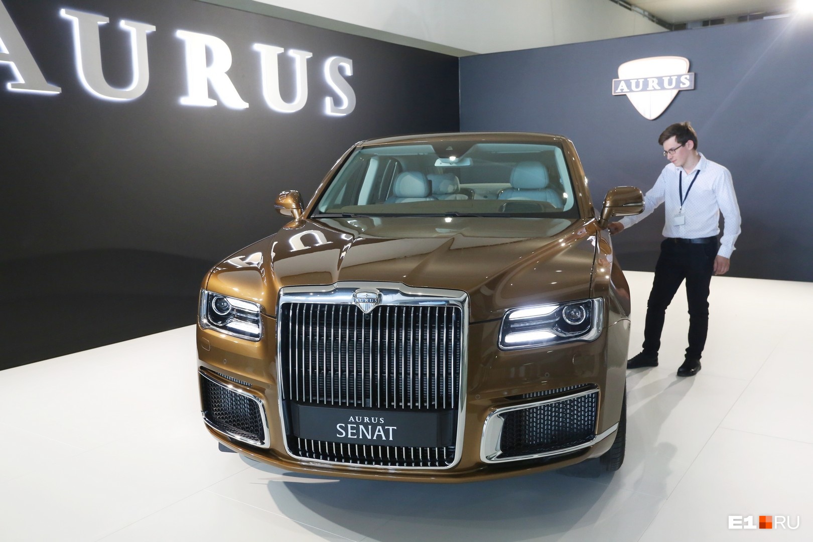 На стенде <b class="_">НАМИ </b>показывают российский автомобиль представительского класса Aurus Senat, на котором ездит президент Владимир Путин (только его автомобиль длиннее). На фото: сотрудник компании, охраняющий авто На стенде <b class="_">НАМИ </b>показывают российский автомобиль представительского класса Aurus Senat, на котором ездит президент Владимир Путин (только его автомобиль длиннее). На фото: сотрудник компании, охраняющий авто