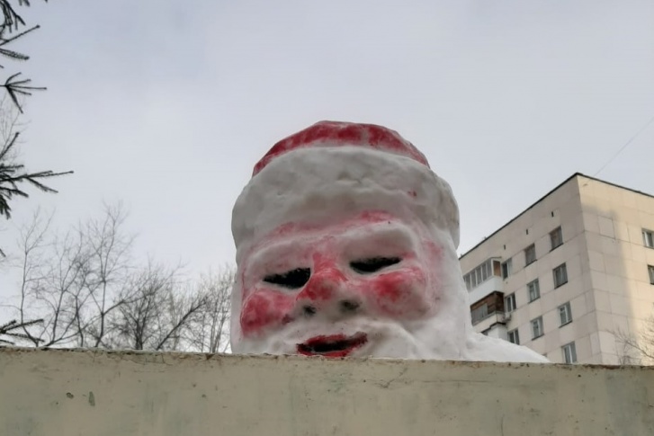 Дед Мороз из фильма ужасов следит за горожанами из-за деревянного ограждения