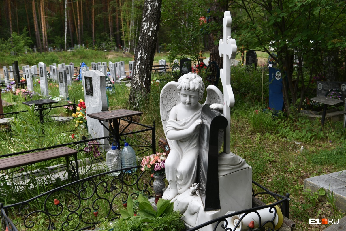 Детское надгробие с ангелом, на земле — игрушечные автомобили
