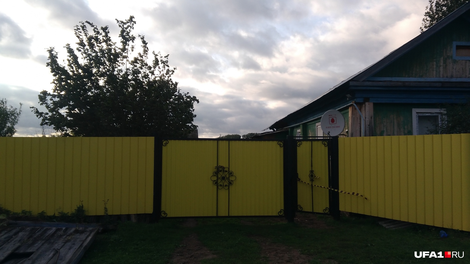Дом, из которого якобы пропал ребенок, забор жизнерадостного ярко-желтого цвета